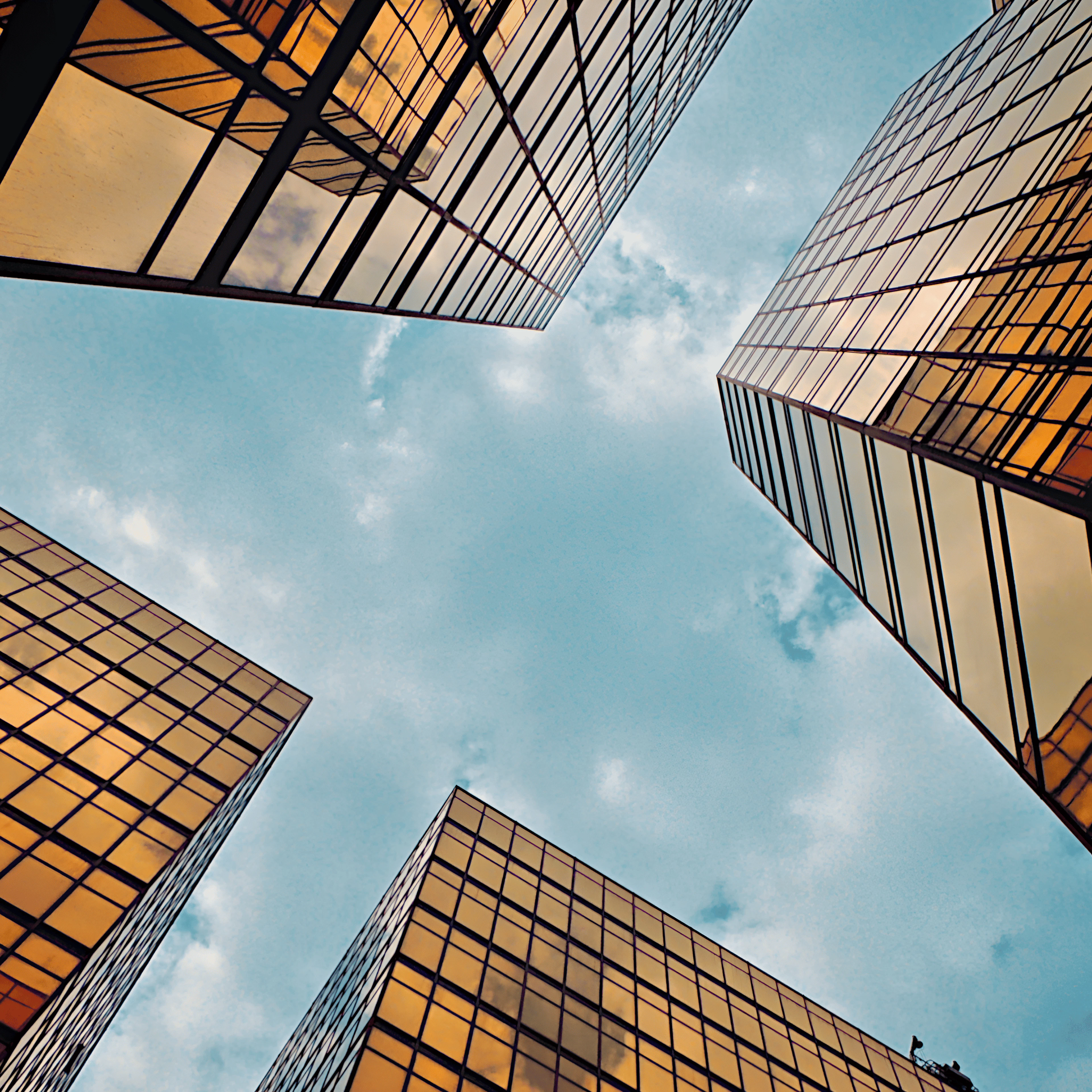 Perspectiva ascendente de edificios corporativos con fachadas doradas, simbolizando las oportunidades de oficinas en Ciudad de México, naves industriales en renta en CDMX y propiedades comerciales premium disponibles en Spot2