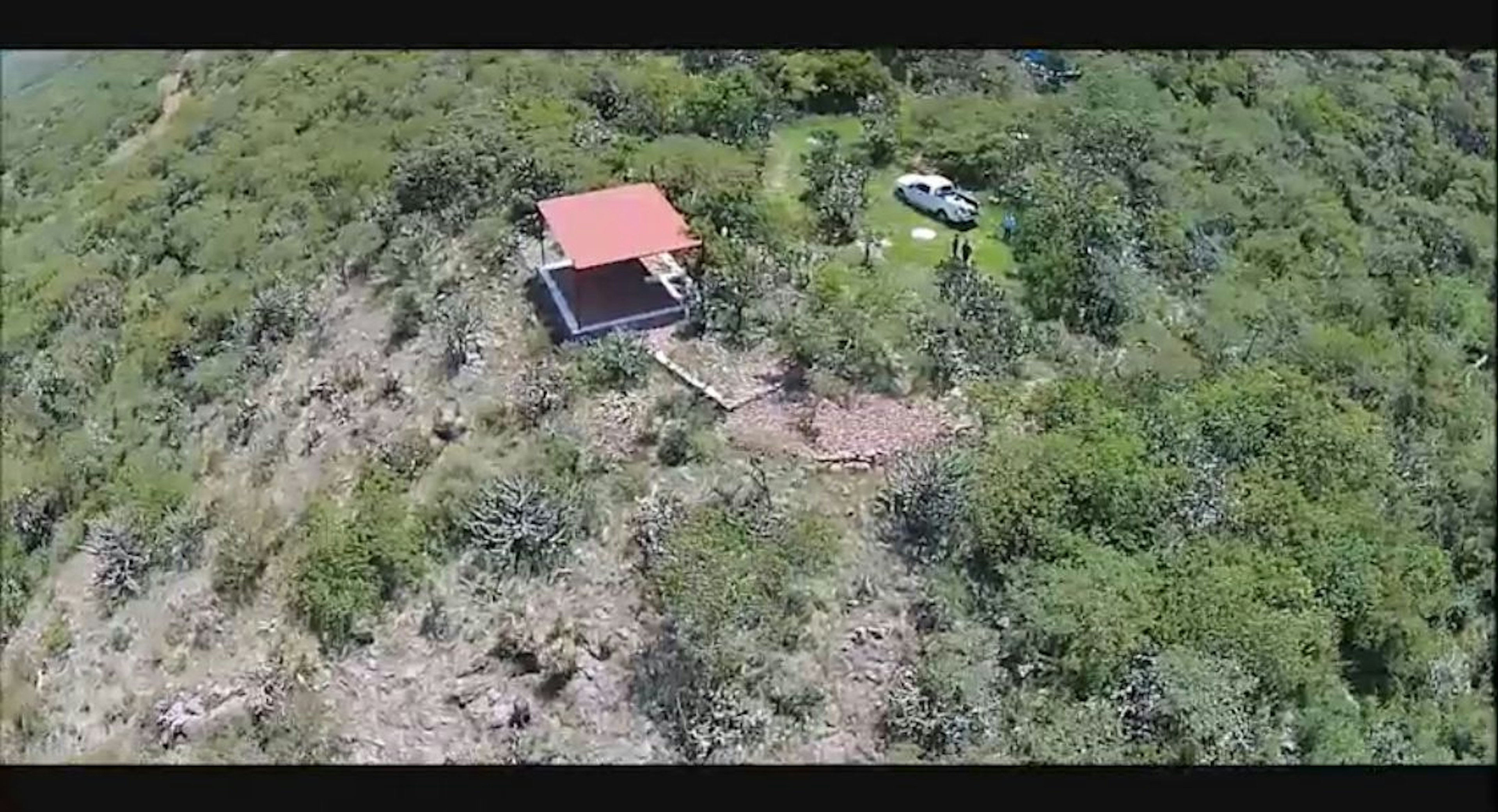 Vista aérea de una propiedad rural con una pequeña casa de techo rojo y un vehículo estacionado. Rodeada de vegetación y árboles, ofrece un entorno natural y privado.