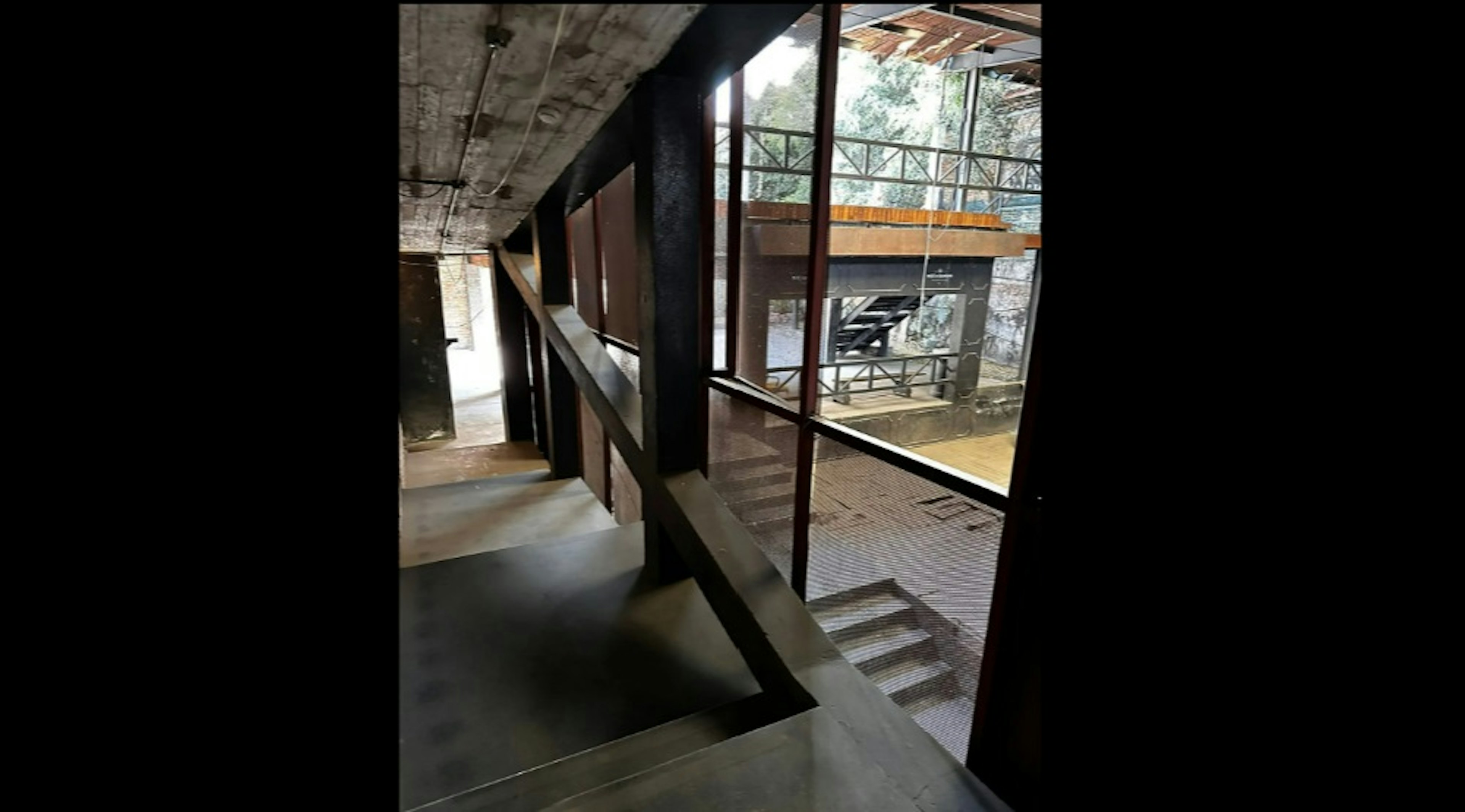 Interior de una propiedad con diseño industrial, mostrando una escalera metálica y pasarelas con barandillas. La combinación de materiales como el concreto y el metal aporta un estilo moderno y urbano.