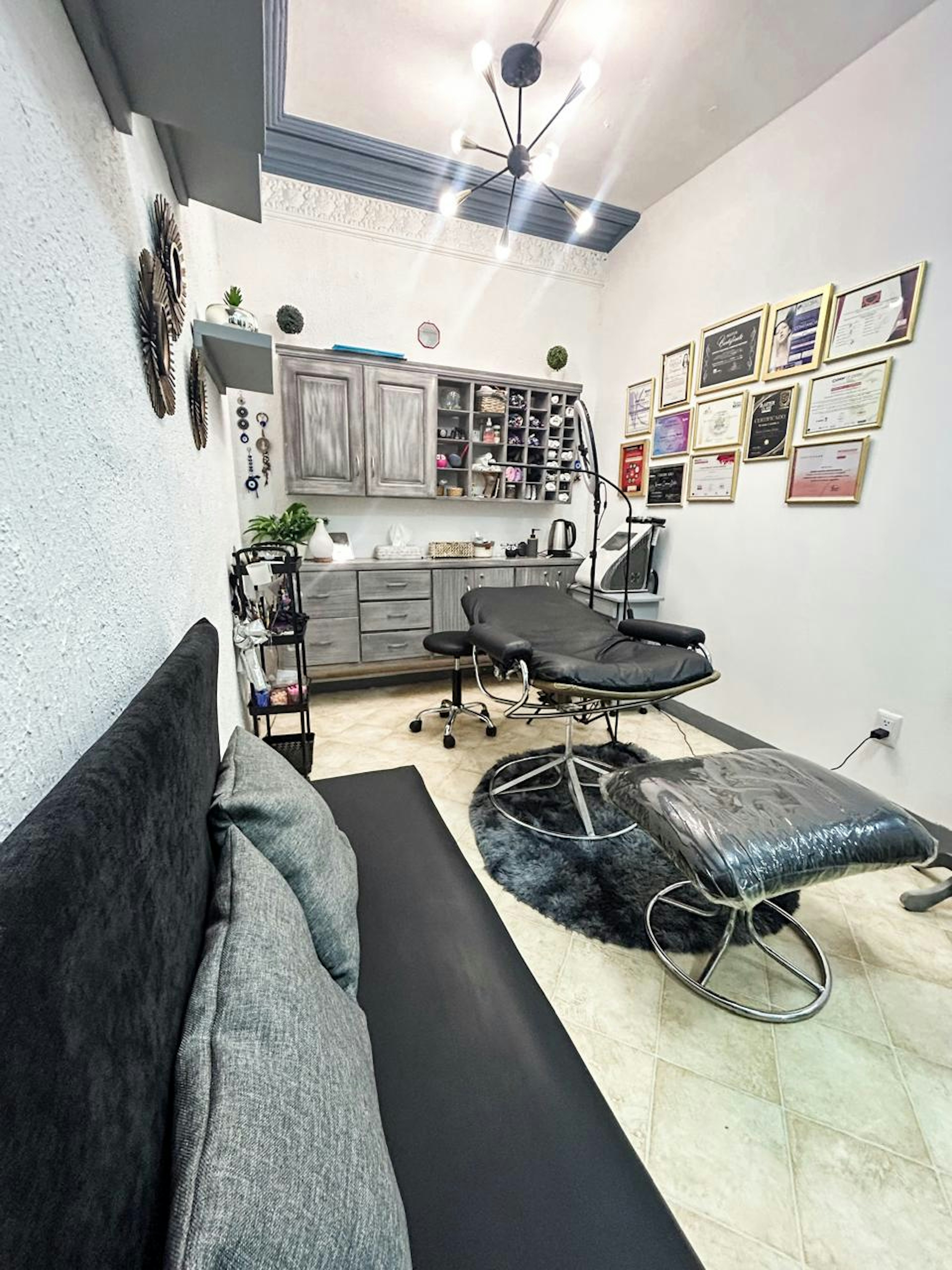 Espacio comercial interior bien iluminado y decorado, utilizado como salón de belleza o estudio de tatuajes, con mobiliario profesional y decoración moderna.