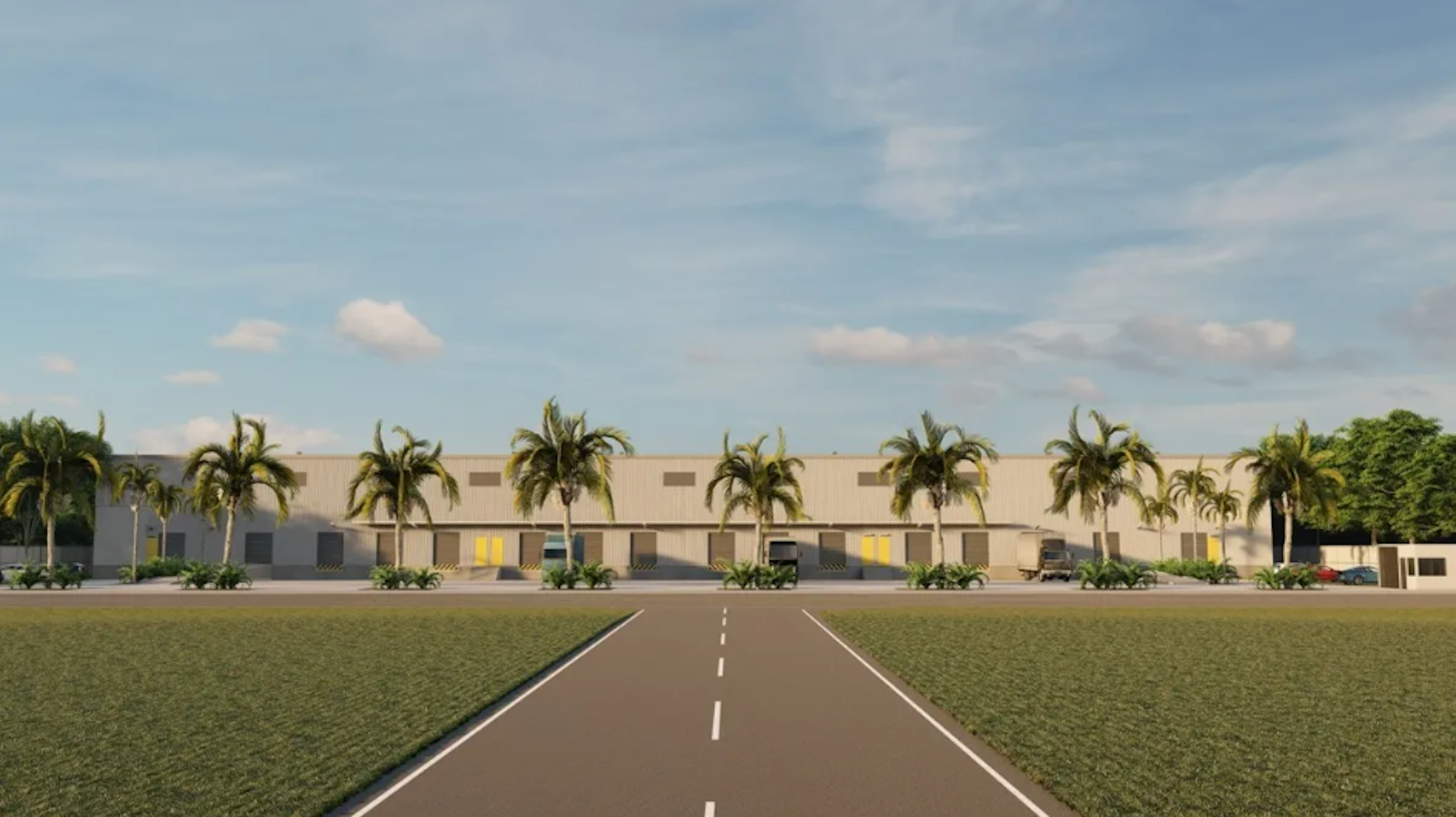 La imagen muestra un complejo de bodegas o naves industriales con un diseño moderno y tropical. La fachada es de color claro, con puertas de acceso amarillas. Una hilera de palmeras bordea el frente del edificio, creando un ambiente atractivo. El complejo está situado junto a una carretera bien pavimentada con líneas divisorias claras. El cielo azul con nubes dispersas completa la escena, sugiriendo un clima agradable.