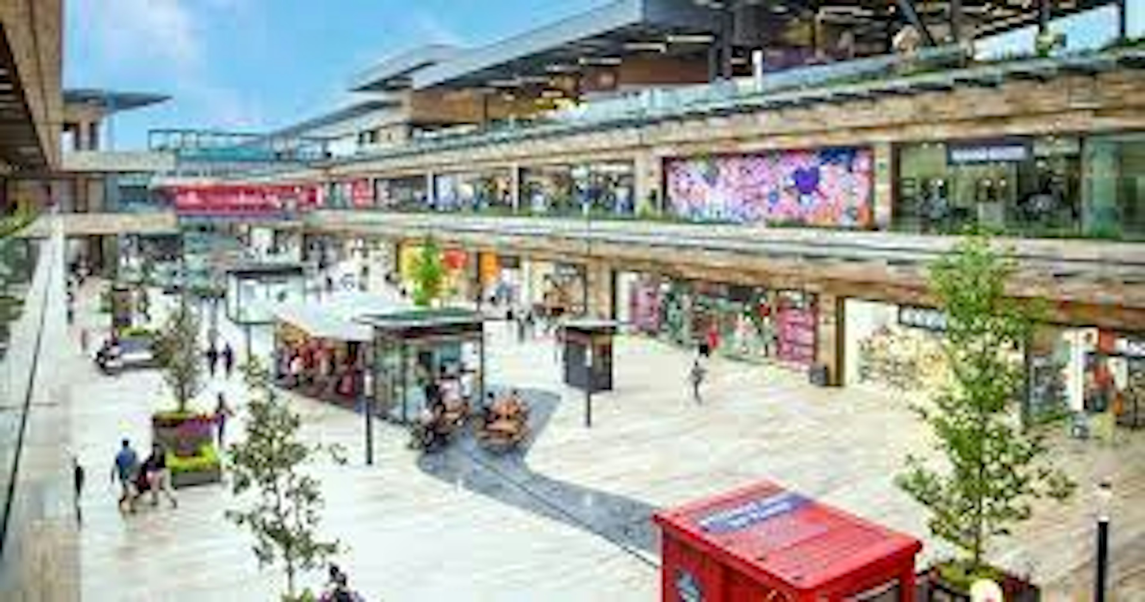 Imagen de un centro comercial al aire libre con múltiples niveles y tiendas variadas. La arquitectura moderna combina elementos naturales y urbanos, creando un ambiente atractivo para compradores.