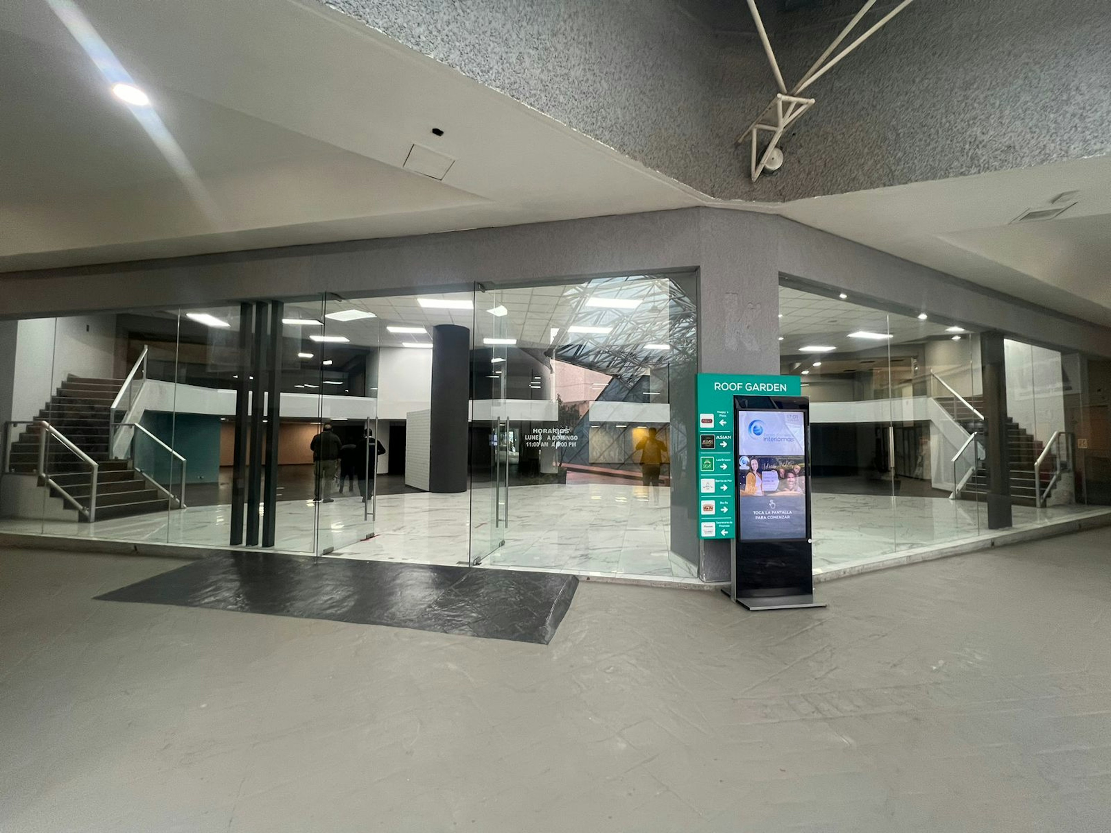 Vista del vestíbulo de un edificio moderno con escaleras, suelo de mármol y acceso de cristal. Ideal para negocios que buscan una entrada elegante y profesional.