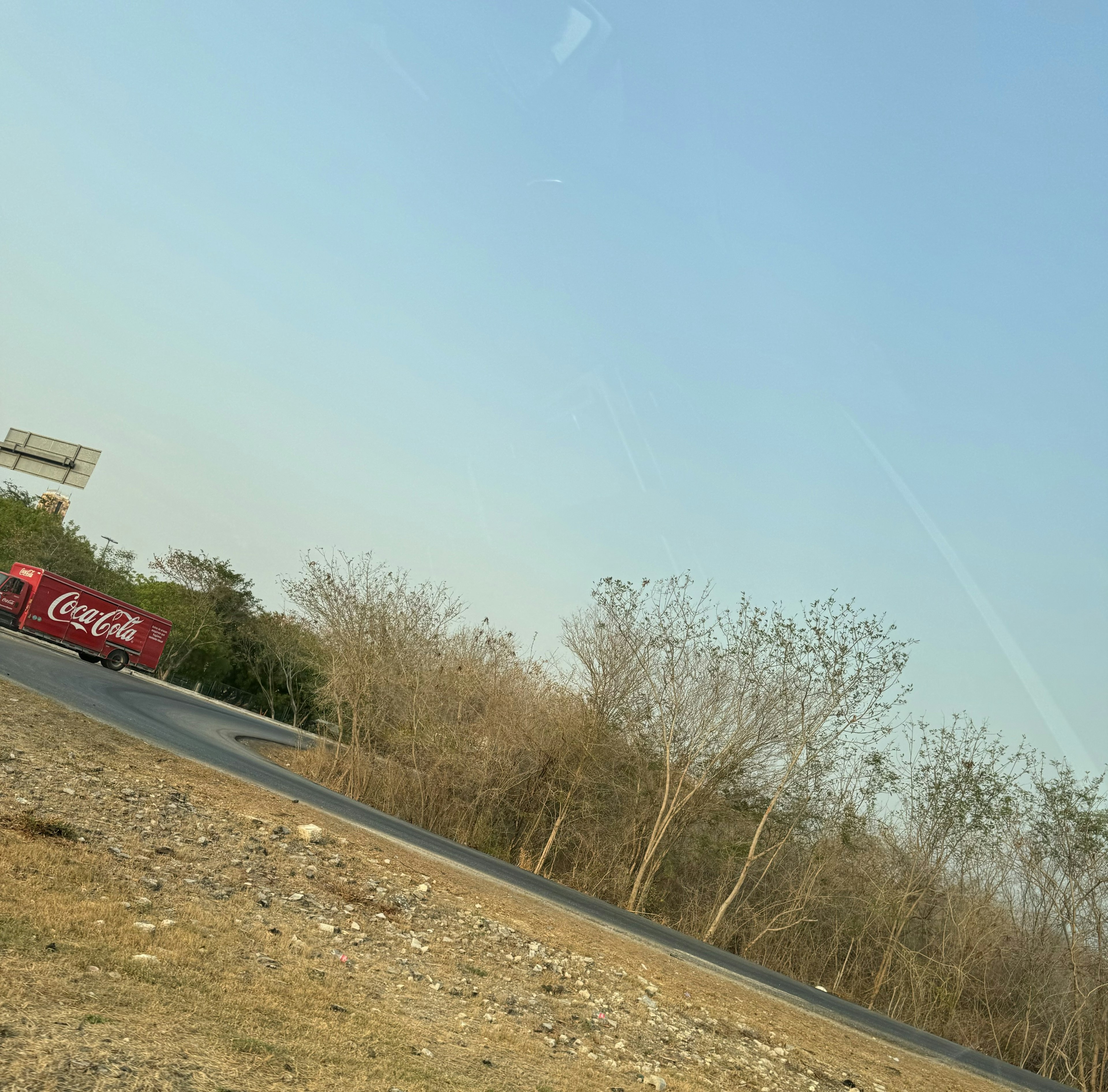 Imagen muestra un terreno con vegetación baja y un camino asfaltado, potencial para desarrollo inmobiliario o comercial.